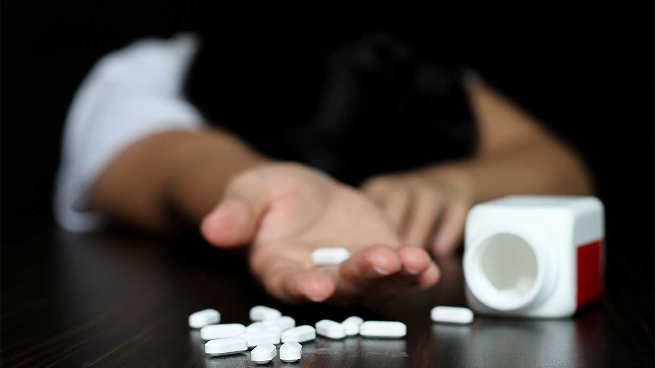 A blurred image of prescription opioids with a background of a person showing signs of anxiety, illustrating the question of do prescription opioids help or hurt anxiety.