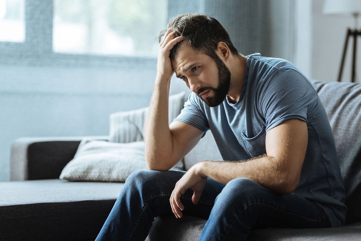 A person looking tired while sitting on a couch, indicating the effects of Suboxone.