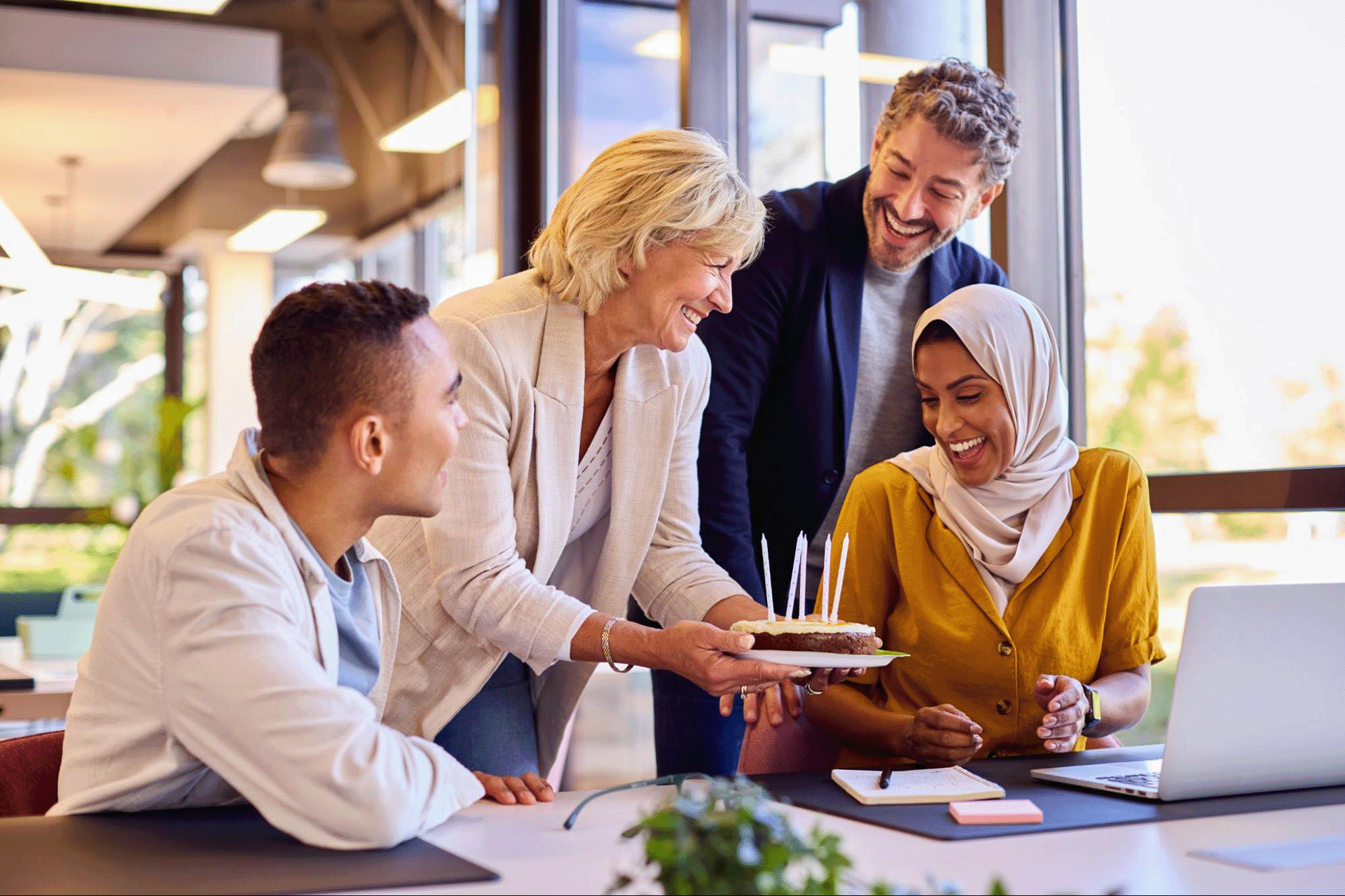 A diverse team celebrating a colleague’s birthday in the office, demonstrating a positive workplace culture built on inclusion, connection, and psychological safety