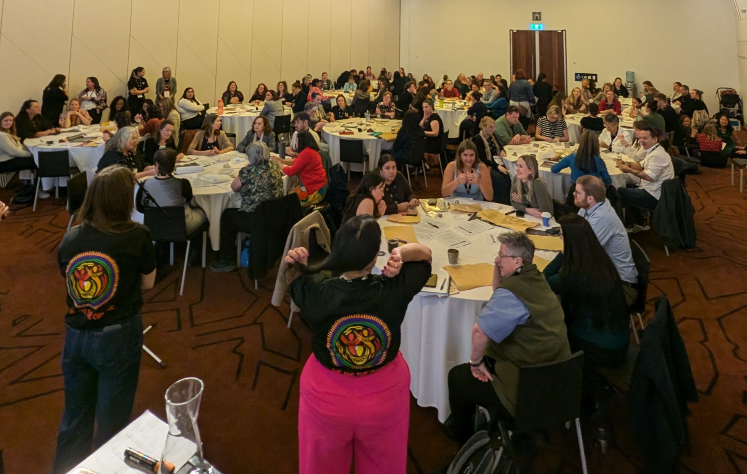 Two women with WYUT shirts looking at crowd of people sitting at tables.