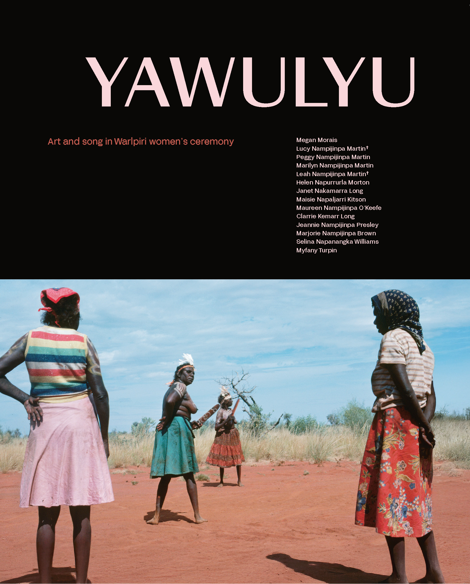 A book or publication cover titled “YAWULYU” in large, soft pink capital letters at the top against a black background. Below the title, the subtitle reads: “Art and song in Warlpiri women’s ceremony” in smaller red-orange text. Aligned on the right side of the black section is a list of contributors’ names, including: Megan Morais Lucy Nampijinpa Martin† Peggy Nampijinpa Martin Marilyn Nampijinpa Martin Leah Nampijinpa Martin† Helen Napurrurla Morton Janet Nakamarra Long Maisie Napaljarri Kitson Maureen Nampijinpa O’Keefe Clarrie Kemarr Long Jeannie Nampijinpa Presley Marjorie Nampijinpa Brown Selina Napanangka Williams Myfany Turpin Below the black upper section is a photograph of Warlpiri women standing on red desert earth under a bright blue sky. The women wear colourful skirts and headscarves, and their bodies are adorned with ceremonial white body paint. One woman in the centre holds ceremonial objects and appears mid-movement in a dance. Tall grass and scattered trees can be seen in the background.