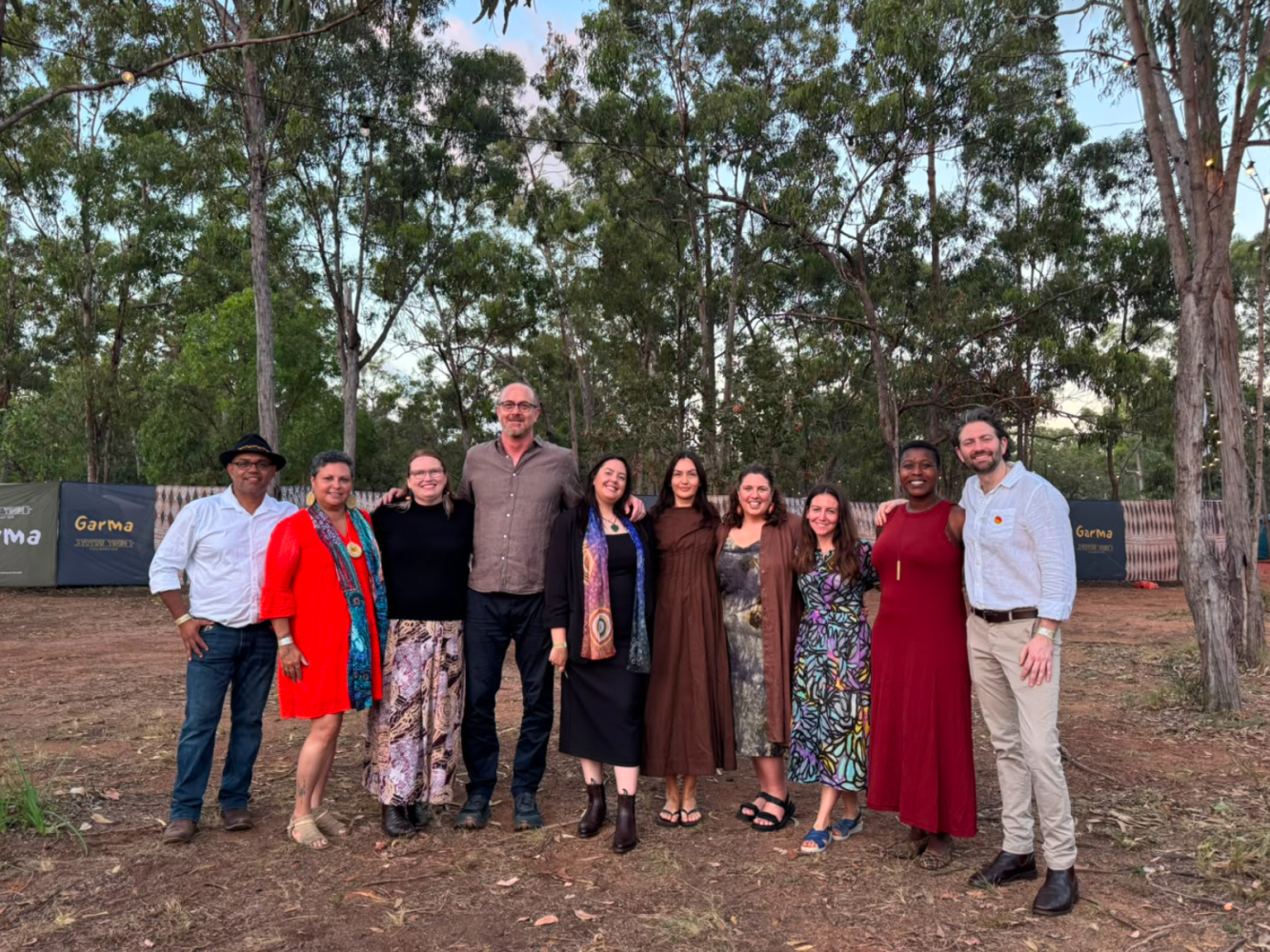 group of people smiling arm in arm at Garma festival outside under trees