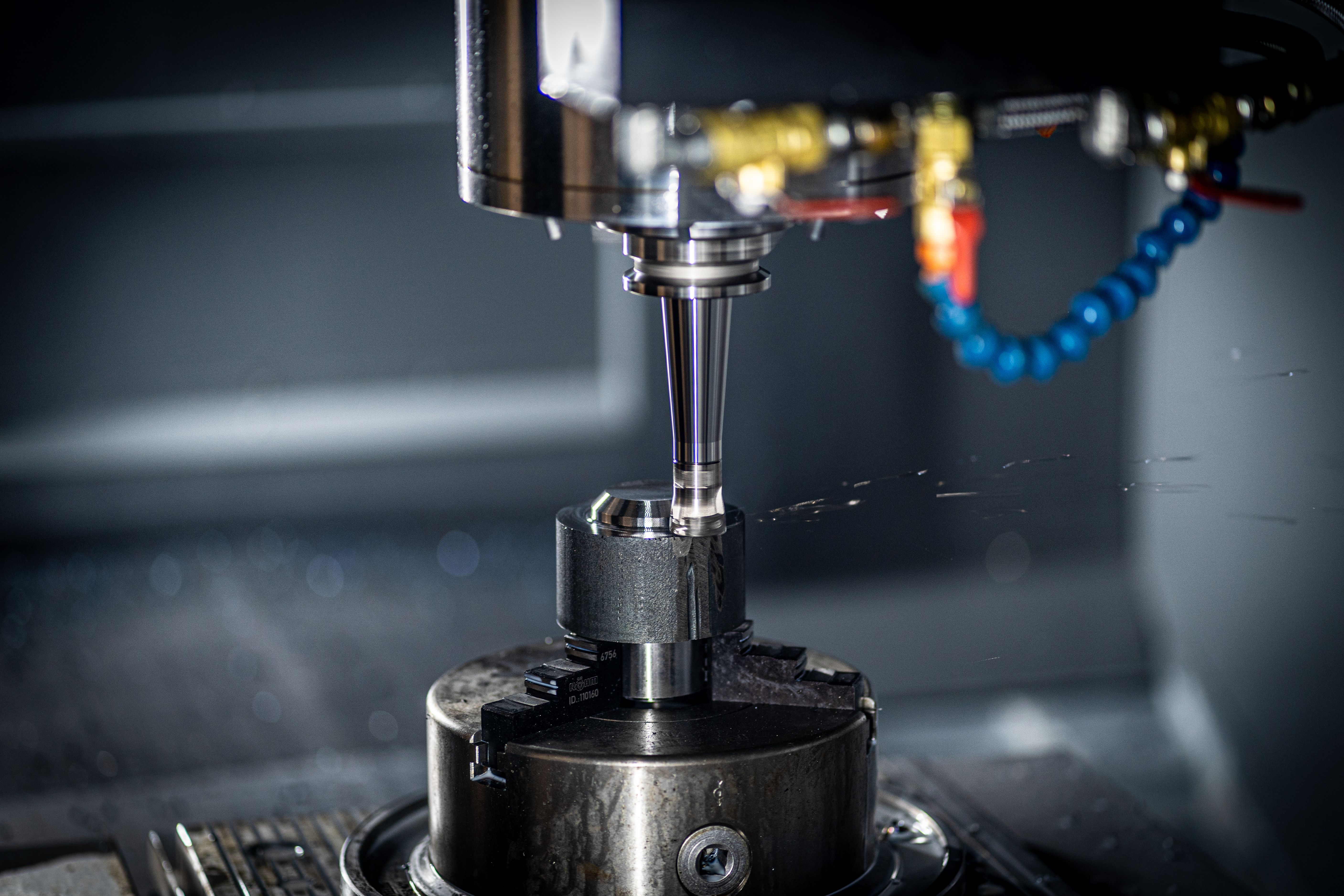CNC mill spindle machining a metal part with coolant, close-up view