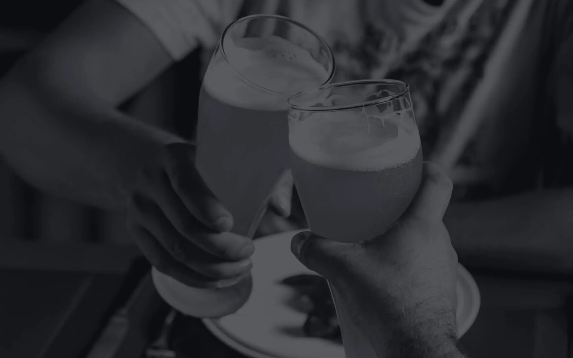 Two men toasting with beer over a pub dinner