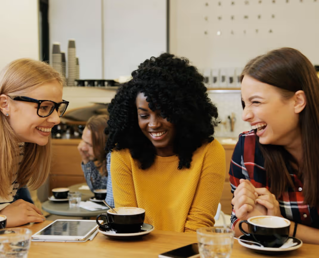 Three friends smiling in a coffee shop