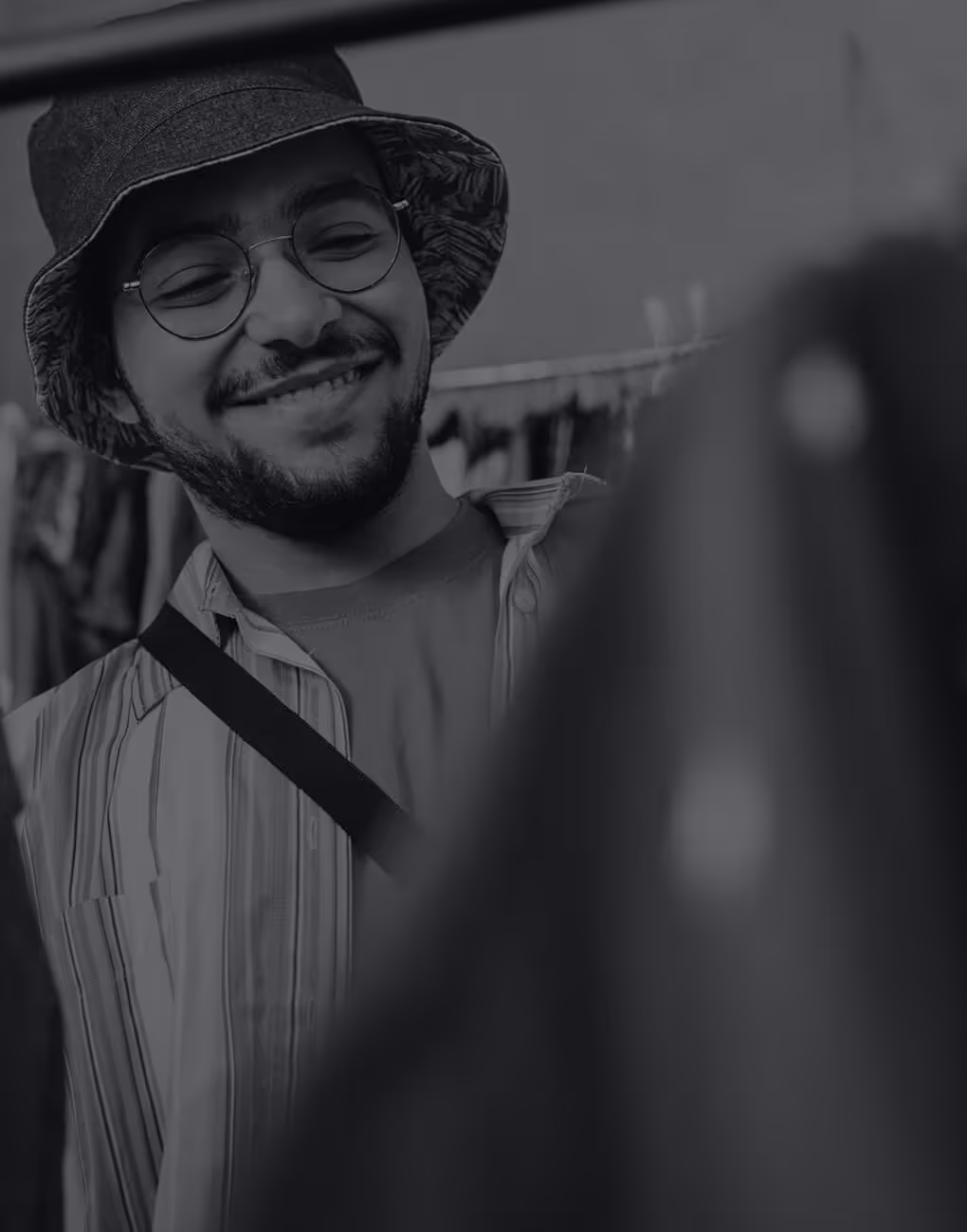 Young man in a bucket hat browsing clothes in a fashion store