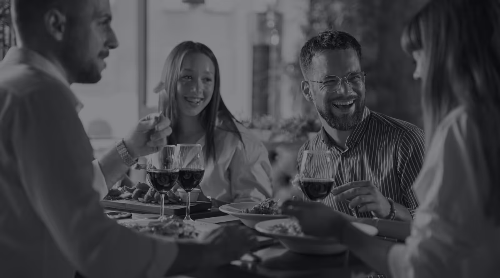 Group of friends smiling and sitting at a table drinking wine