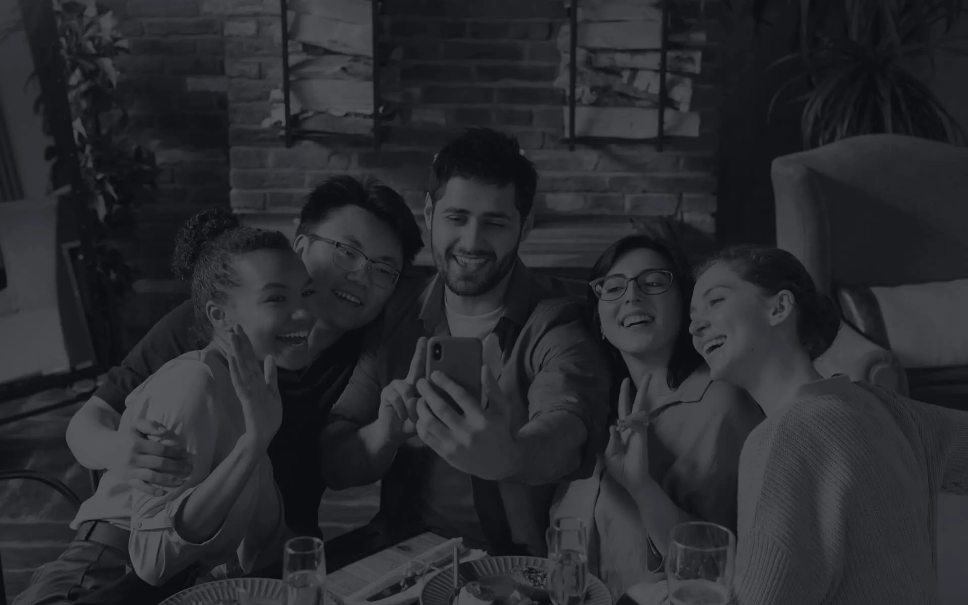 Group of friends posing for a selfie at a restaurant table