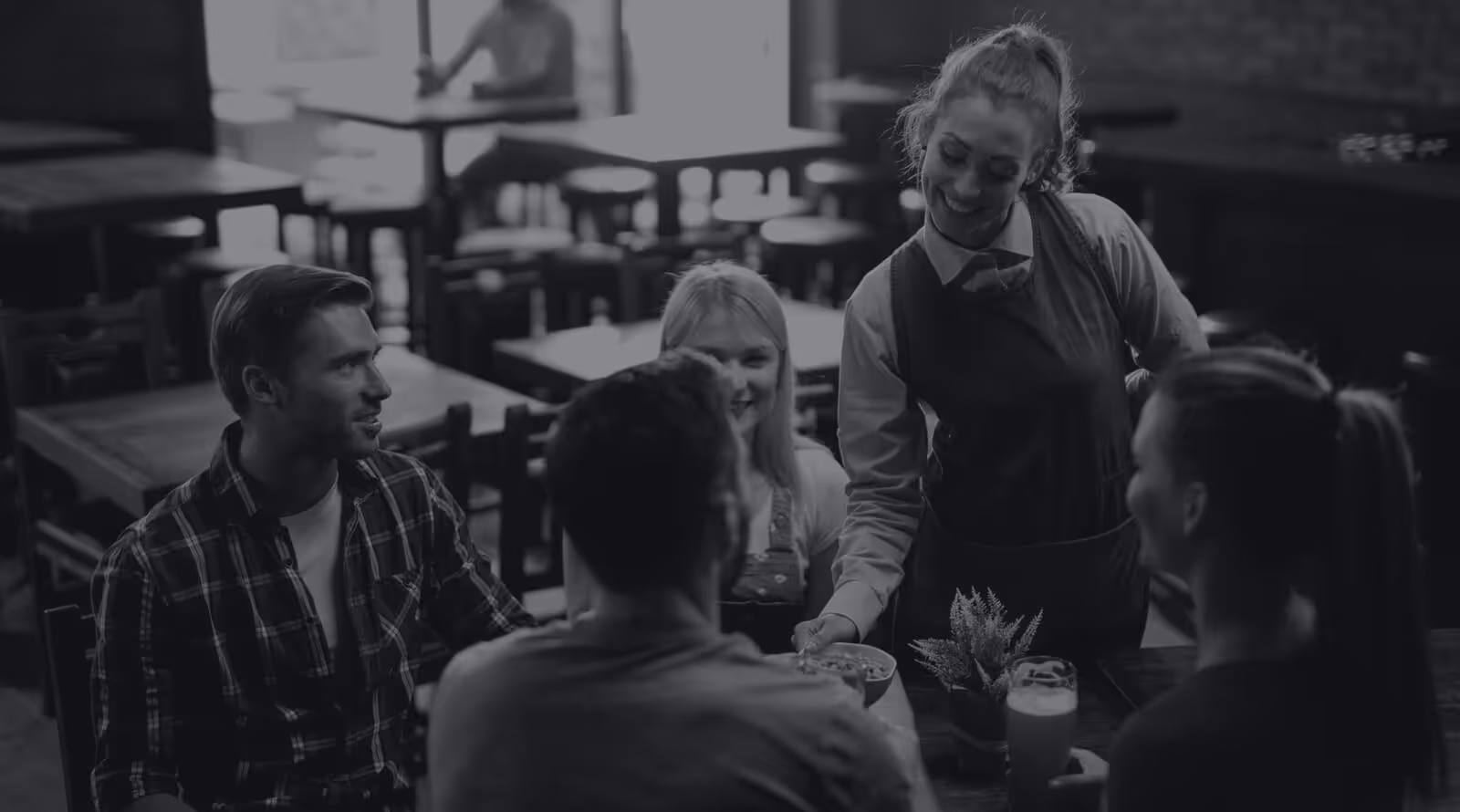 Waitress serving food to a group of friends in restaurant