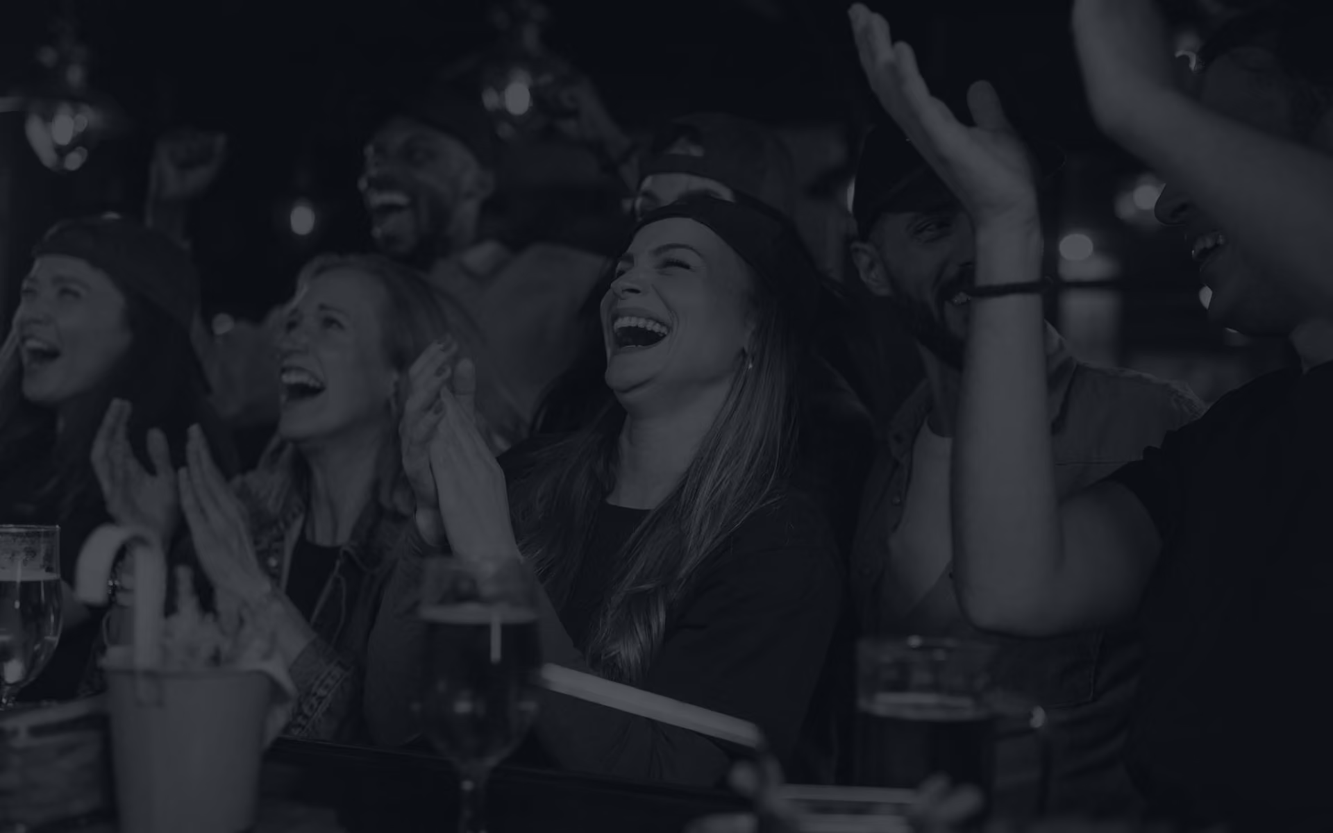 Group of friends laughing and clapping together at a bar or pub.