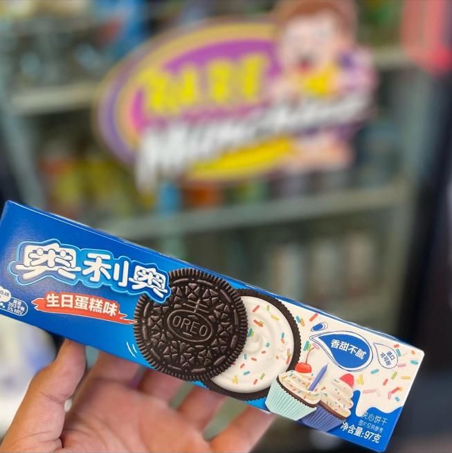 This may contain: a person holding up an oreo cookie in front of a store display case with chinese characters on it