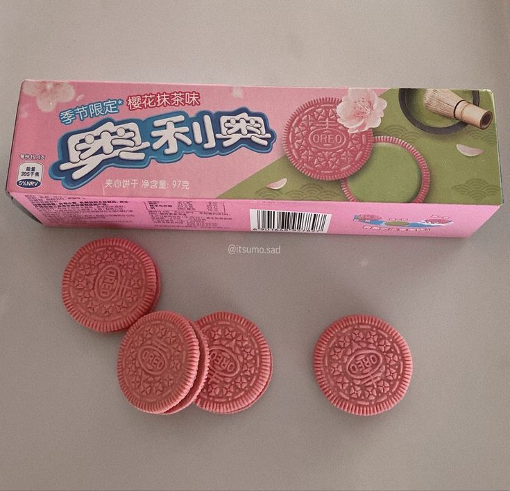 This may contain: three pink cookies are in front of a box with chinese writing on it and the package is next to them