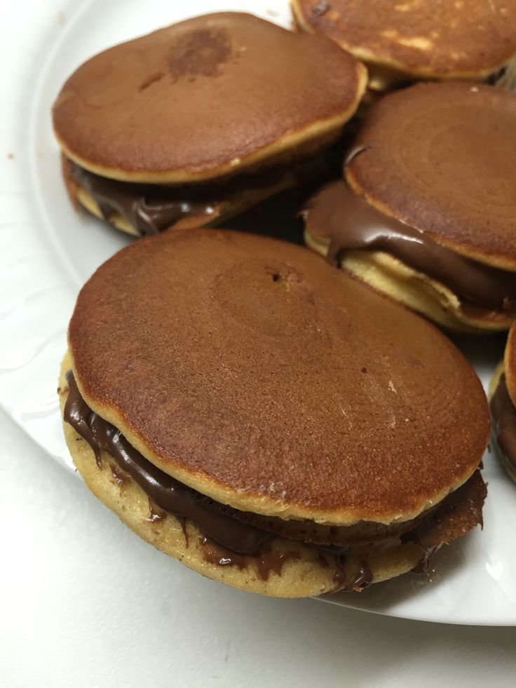 This may contain: some pancakes with chocolate frosting on top of each one sitting on a white plate