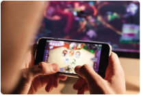 Two gamers sitting on a couch, wearing headsets and holding controllers, playing together on a console game. Both are focused and immersed in the game, with a colorful fantasy game scene displayed in the background. No in-game advertising is visible.