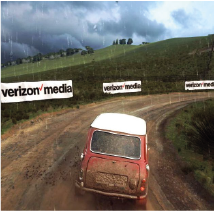 Racing video game showing a red car driving on a muddy road during rain, with multiple Verizon Media banners displayed along the track as in-game advertising.