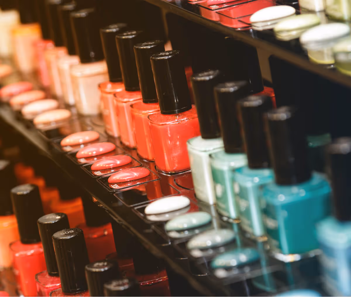 Rows of nail polish bottles in various colors including red, peach, and teal on a display rack.