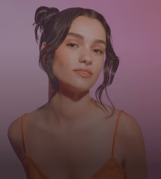 Young woman with dark hair styled in buns, wearing an orange spaghetti strap top against a purple background.