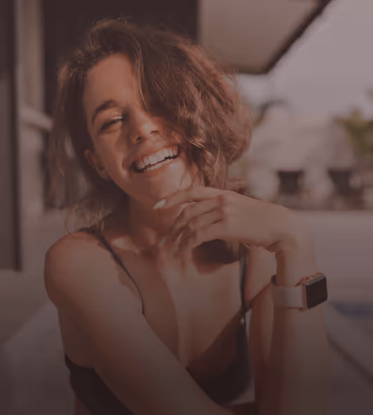 Smiling young woman with short wavy hair wearing a fitness tracker on her wrist.