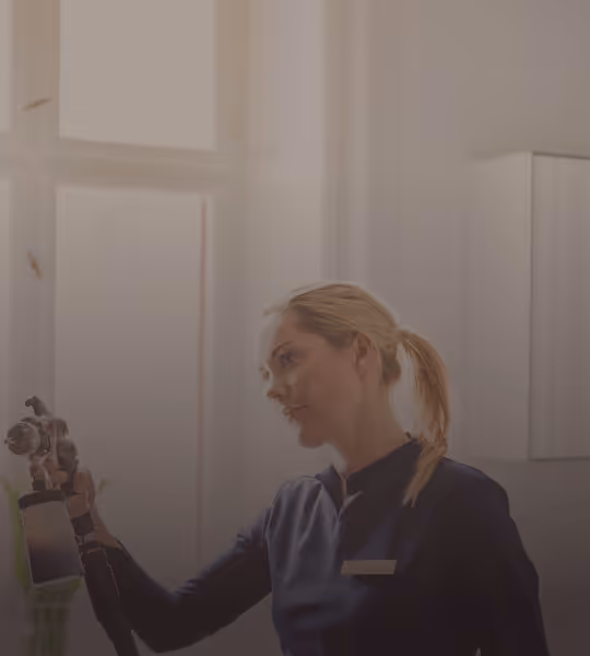 Woman holding a spray tanning device in a bright, modern room.