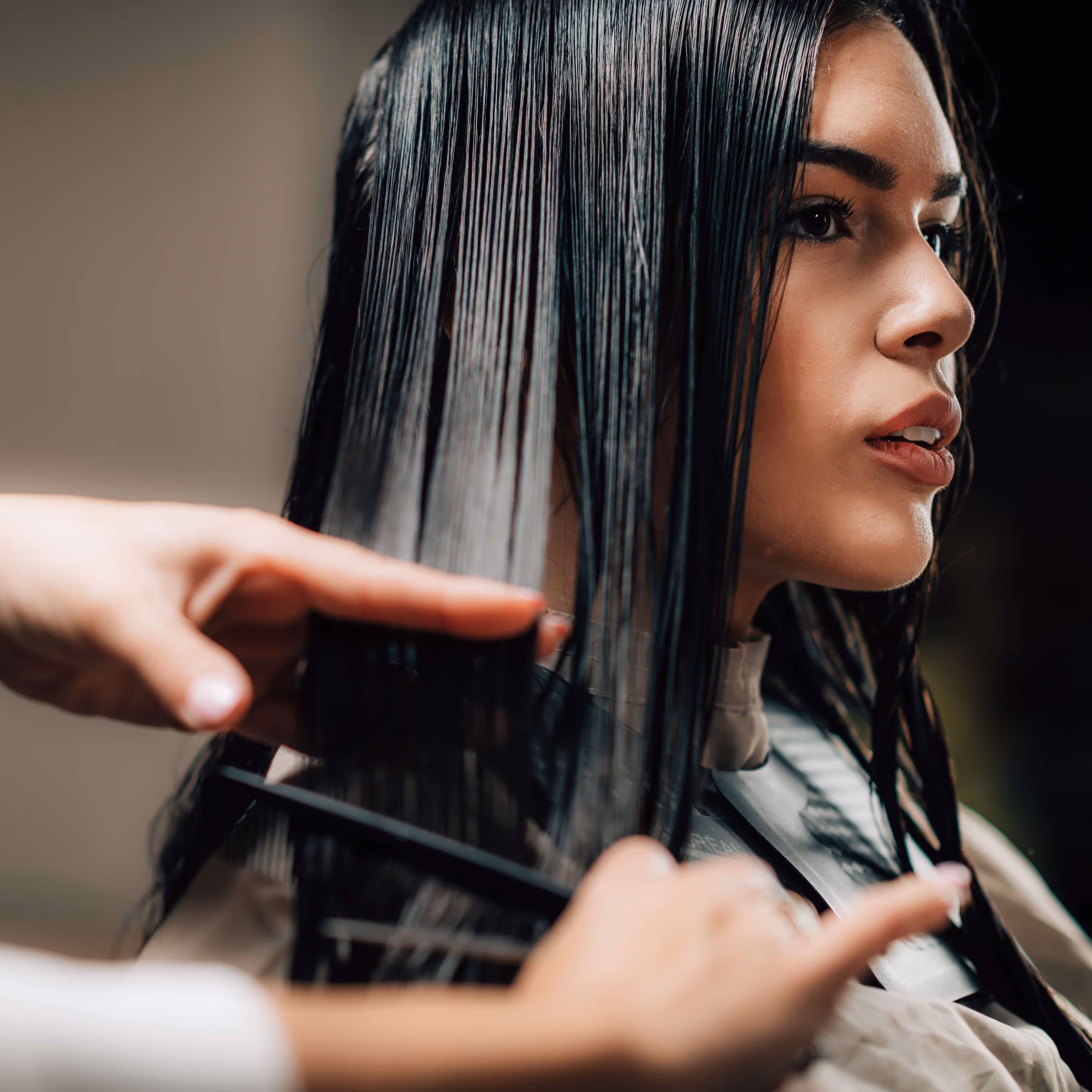Close-up of a woman with wet hair being combed during a haircut.