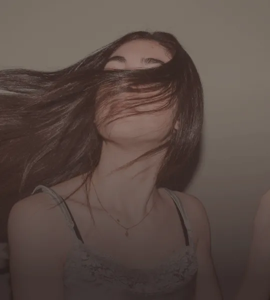 Young woman with long hair swept across her face against a plain background.