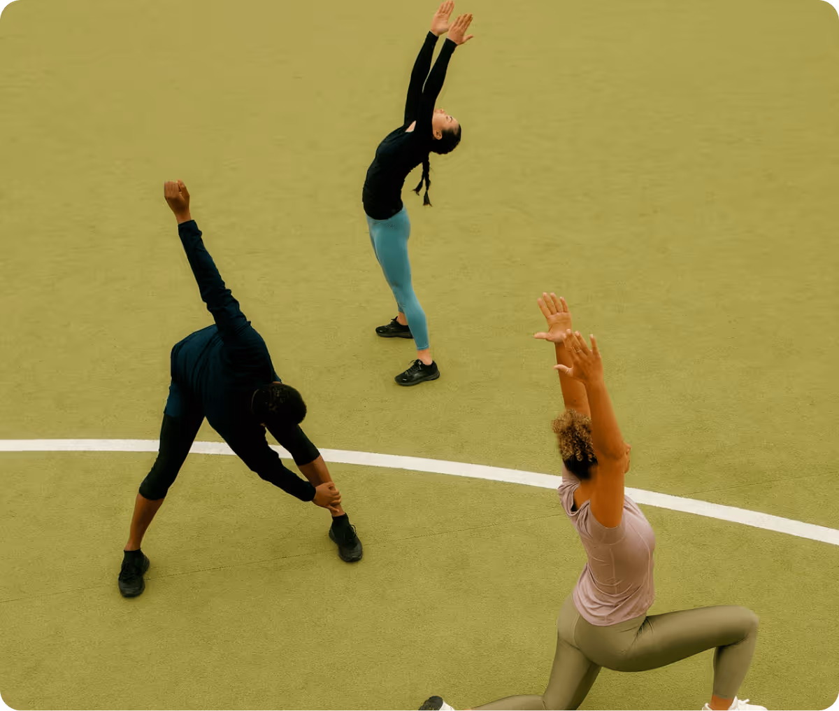 Three people stretching outdoors on a green sports field, performing different fitness poses.
