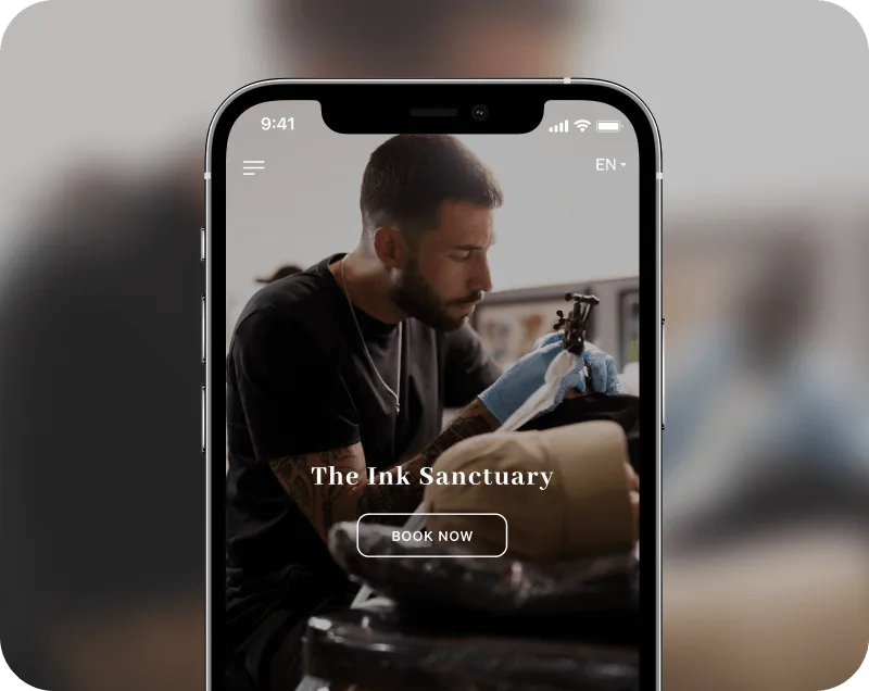 Tattoo artist wearing blue gloves focusing on tattooing a client's arm, displayed on a smartphone screen with 'The Ink Sanctuary' and a 'Book Now' button.