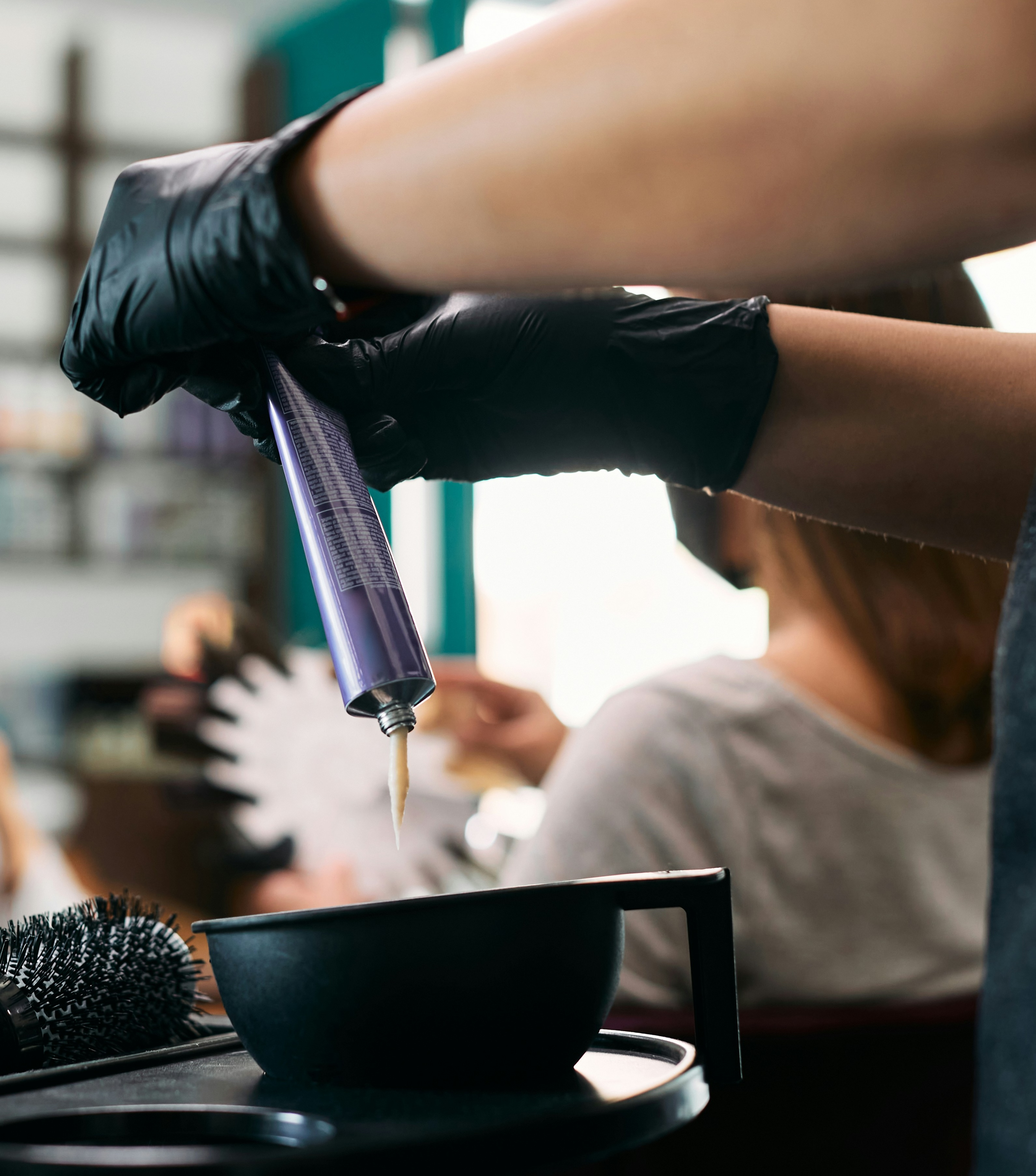 Professional hair colorist mixing developer and color in a tint bowl