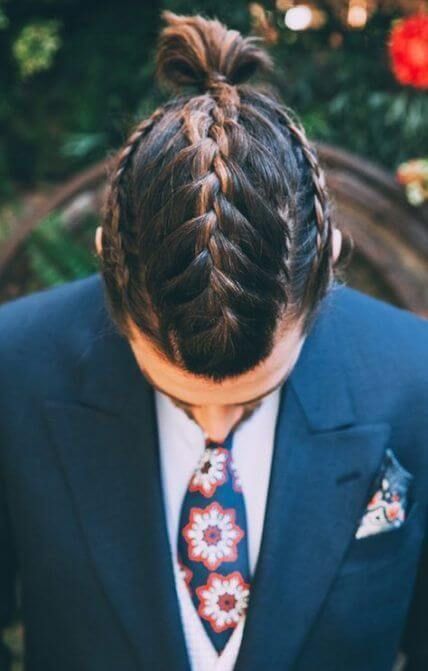 Man with two French braids for men pulled into a top bun wearing a suit
