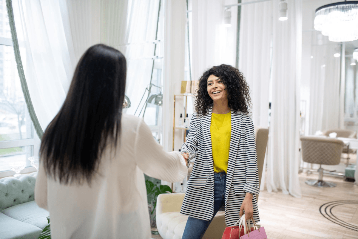 A hair salon specialist welcoming a returning client with a handshake in a luxury salon interior
