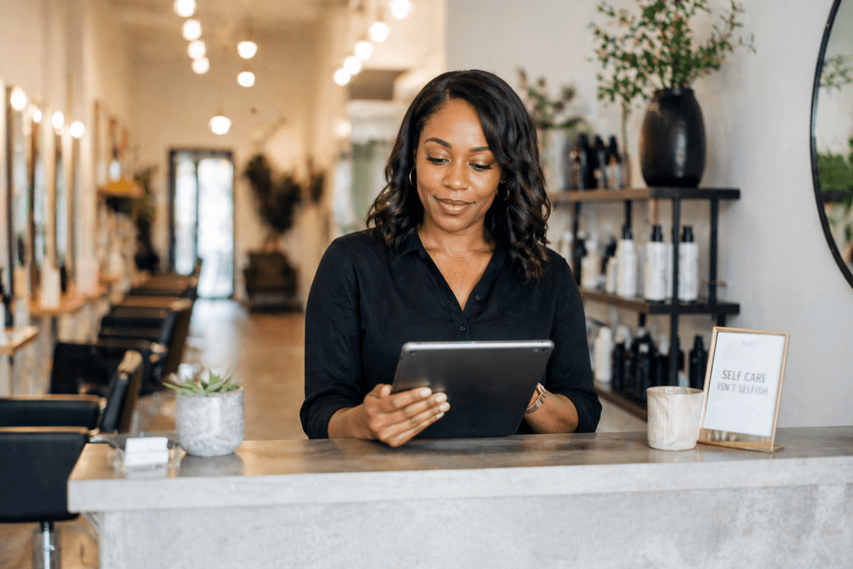 A salon owner reviewing her digital loyalty program setup on a tablet at the reception desk