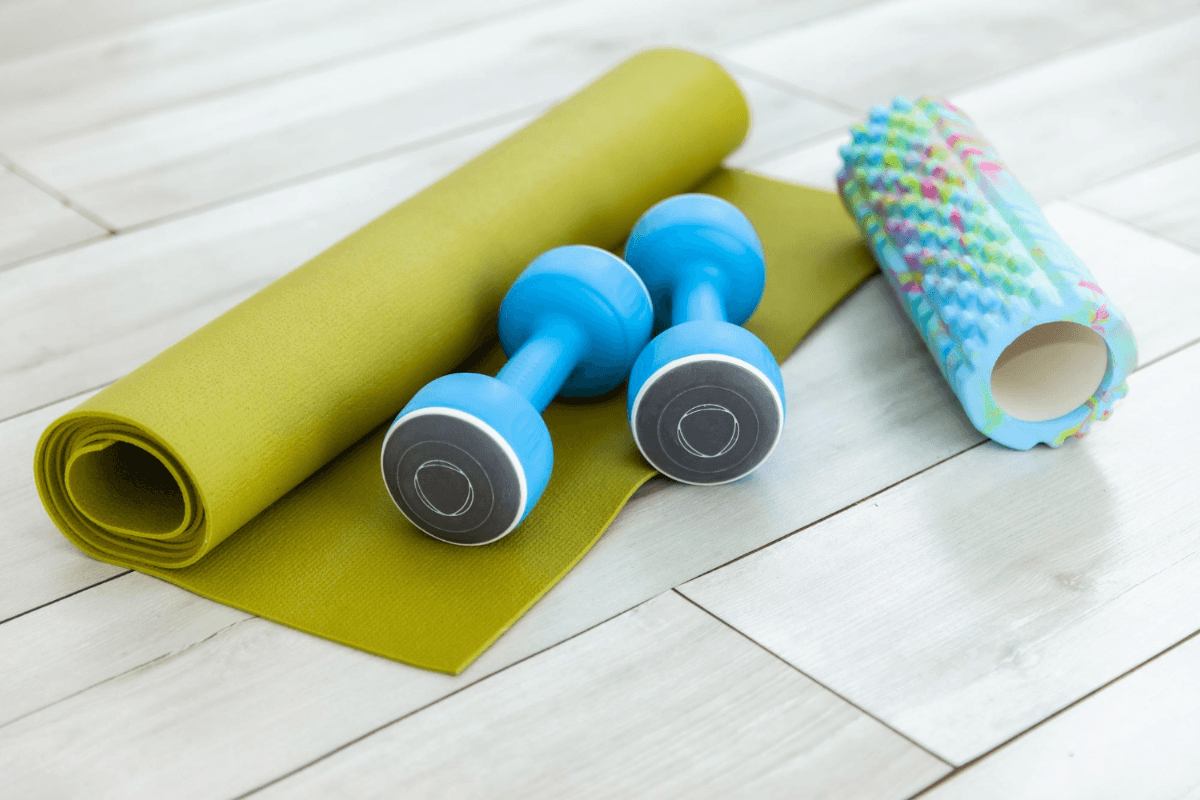 Mat Pilates setup with exercise mat, dumbbells and foam roller