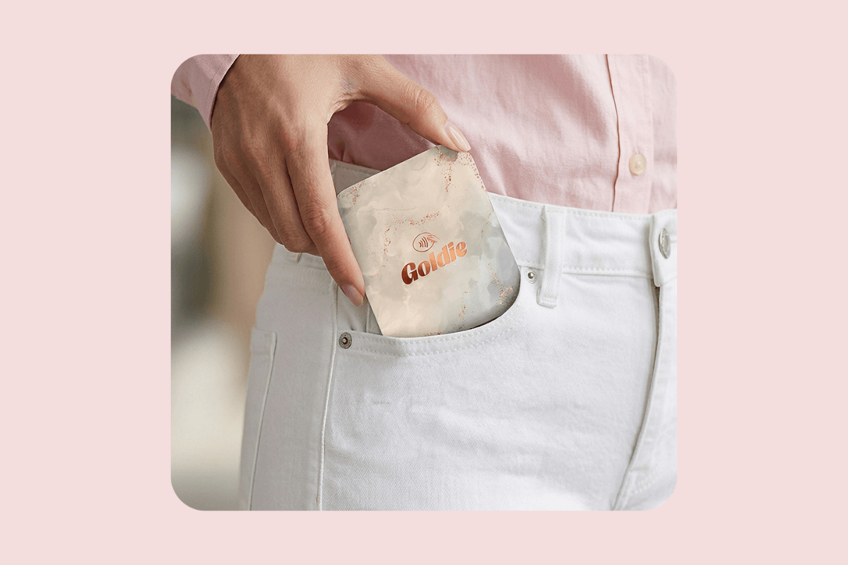 Hand holding a portable Goldie card reader for mobile in-person payments at a salon