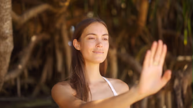 A woman holding up her hand in a forest of branches.