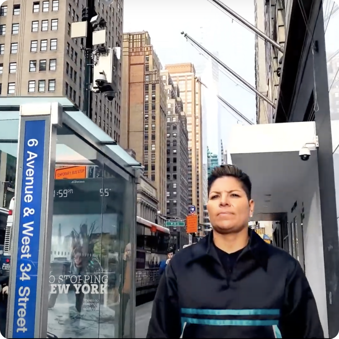 A person in front of a bus and tall buildings