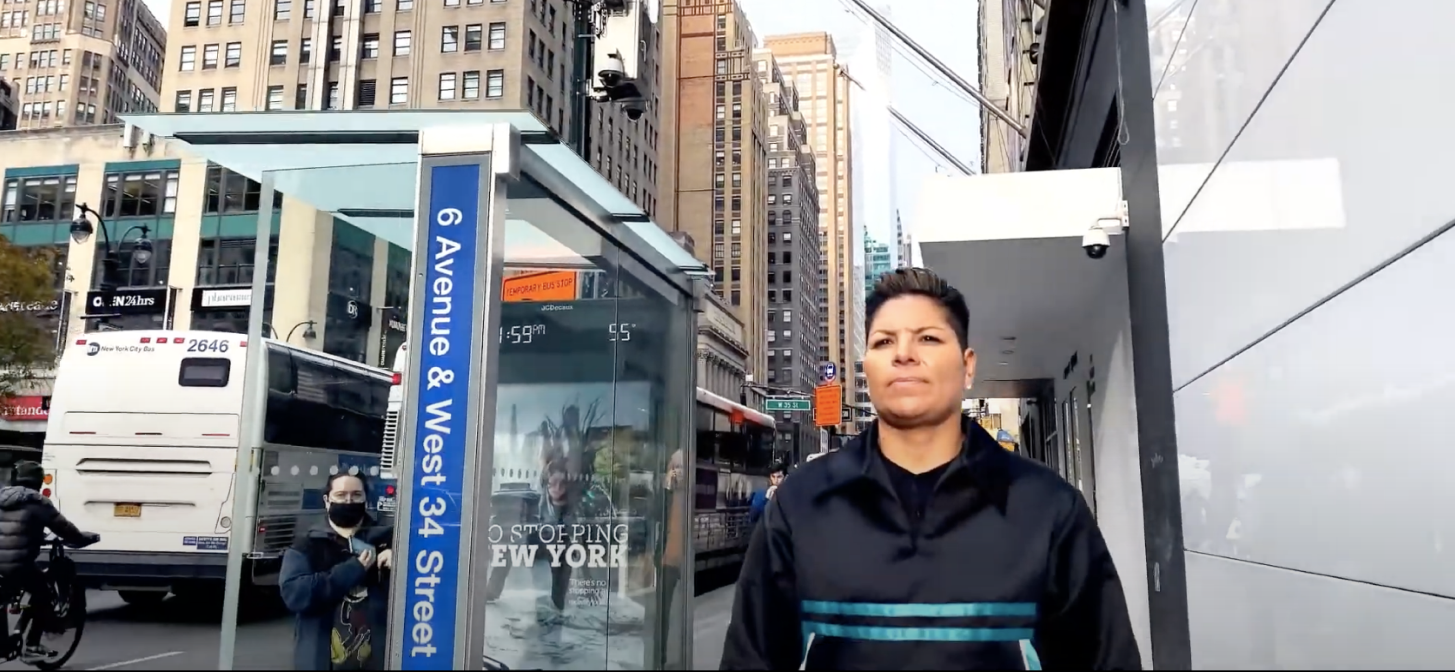Person standing in front of a bus stop and tall buildings