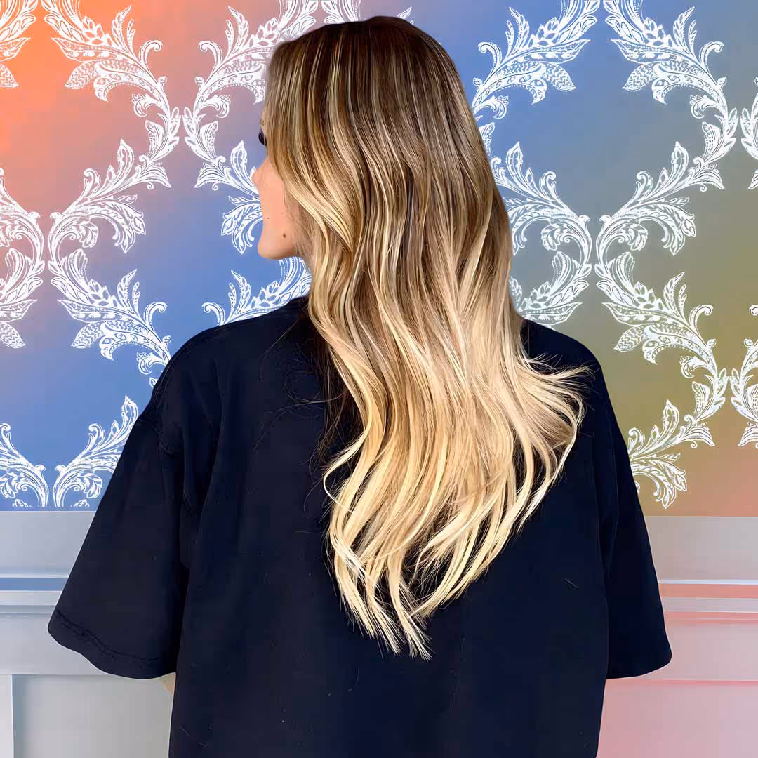 Luxurious blonde balayage hair extensions showcasing perfect color blend and natural movement against pattern background