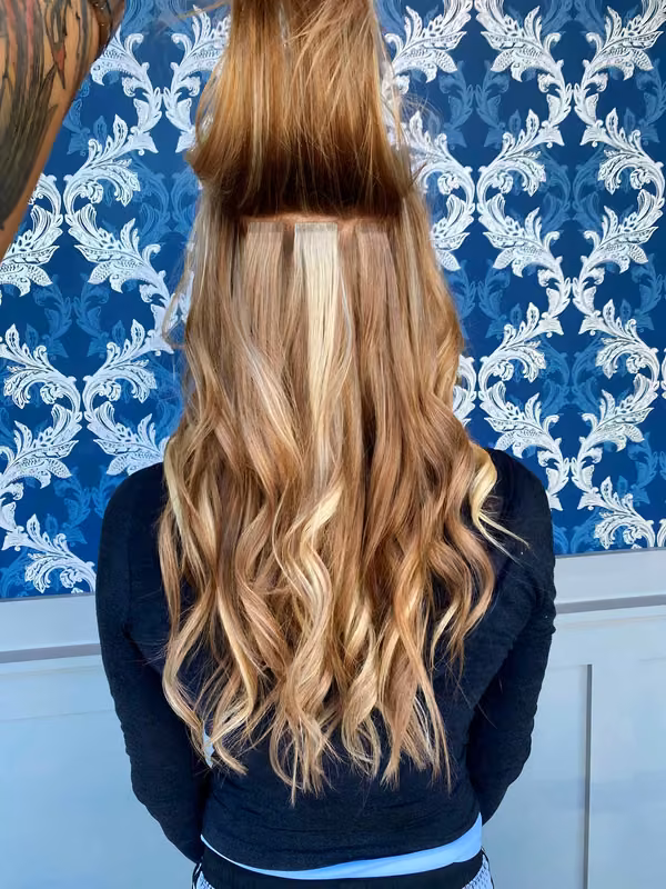 Professional blonde wavy hair extensions showcasing natural movement and perfect blend against signature blue pattern backdrop