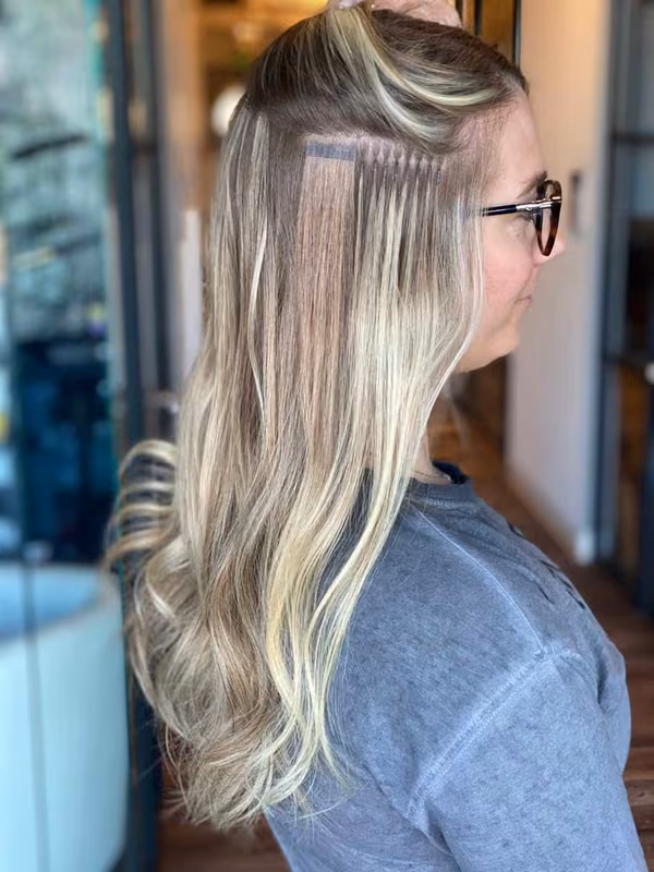 Side view of expertly applied keratin bond extensions showing seamless integration with natural blonde hair