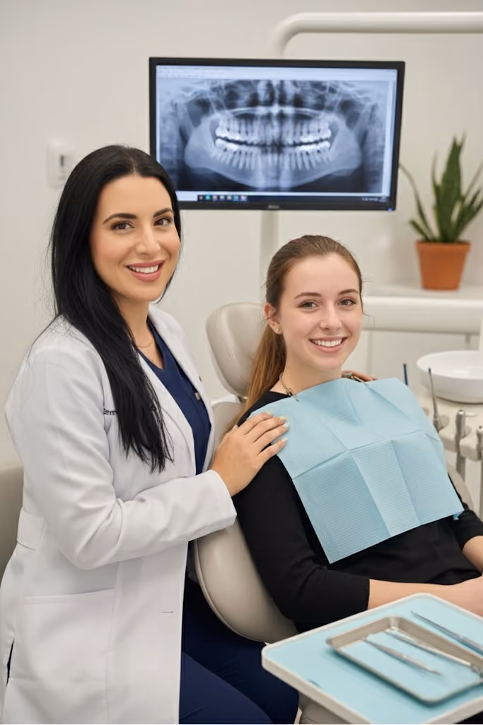 Dentist beside a smiling patient in a treatment chair
