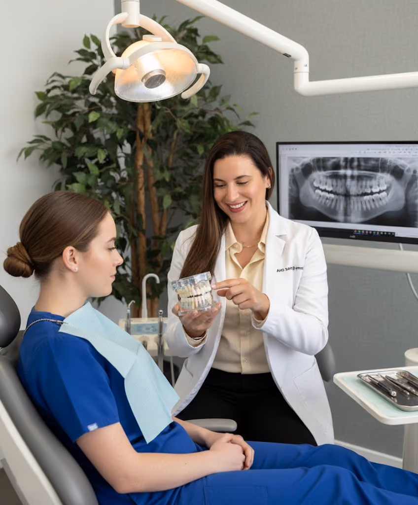 Dentist explaining dental care to a patient using a model of teeth