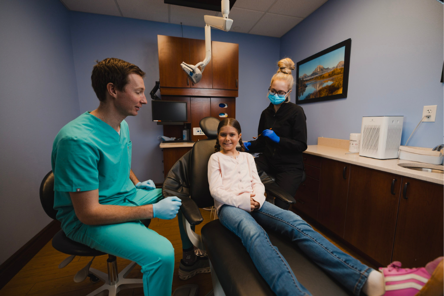 Pediatric dentist and dental assistant helping a young patient feel comfortable during a children's dental appointment in a modern pediatric dental office.