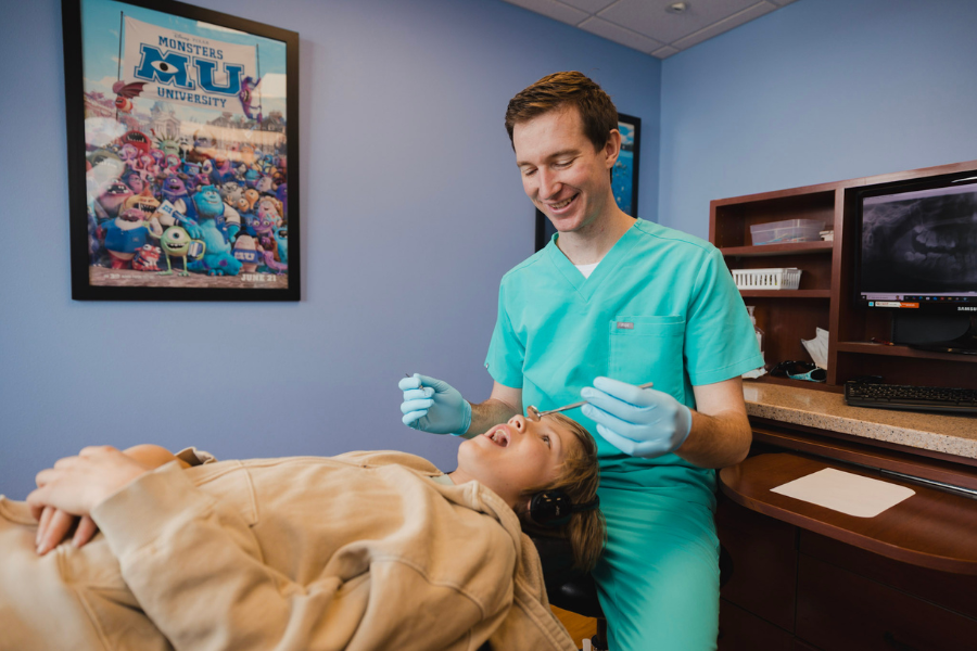 Pediatric dentist examining a young patient’s teeth during a routine dental appointment at Just 4 kiDDS.