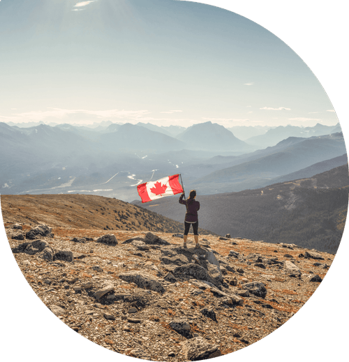 A person holding a Canadian Flag on a mountain