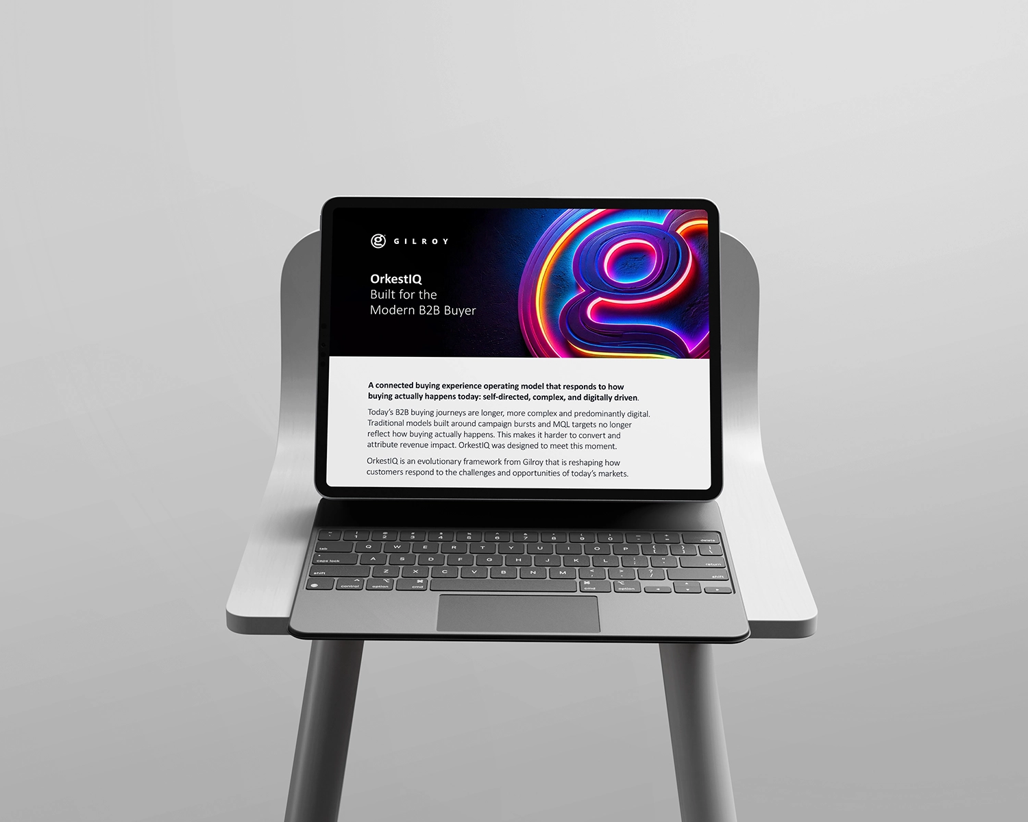 Tablet on a keyboard stand displaying the Gilroy OrkestIQ product sheet, placed on a white chair against a minimalist grey background.
