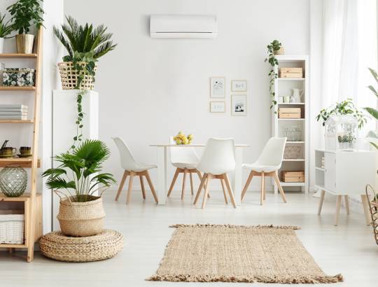 Climatisation murale Kazendo d'Atlantic dans un salon blanc avec des plantes.