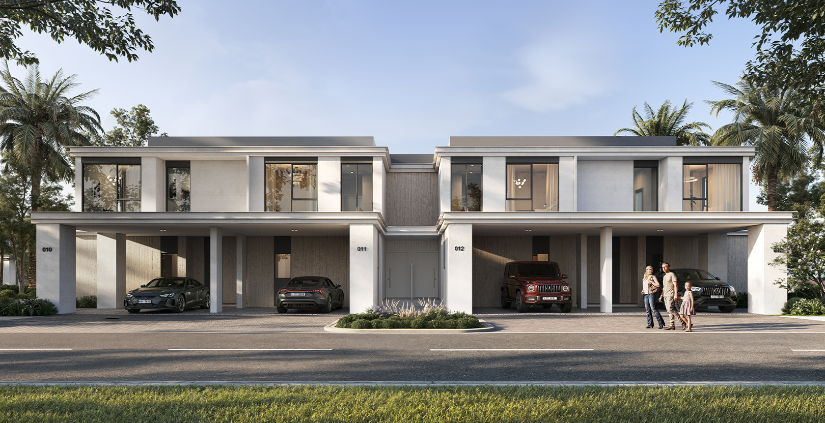 Modern townhouses at Greenville in Emaar South, featuring a driveway with luxury cars, palm trees, and a family standing outside their home