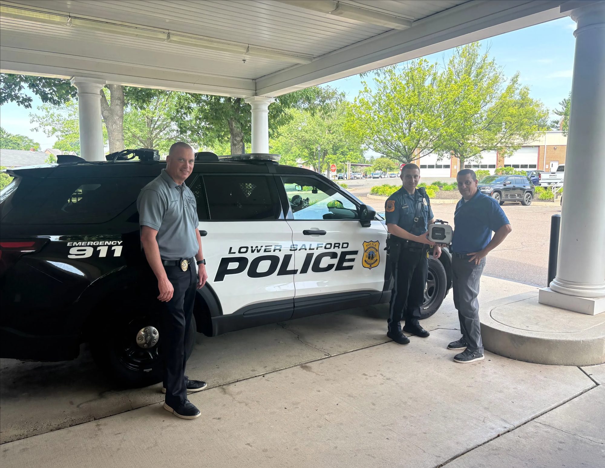 Lower Salford police officers with an Avive Connect AED next to a patrol car