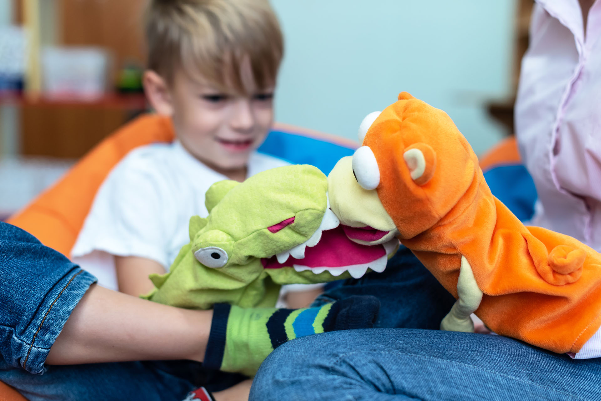Child engaging in playful puppet interaction during a first therapy session, building rapport and comfort in a supportive setting.