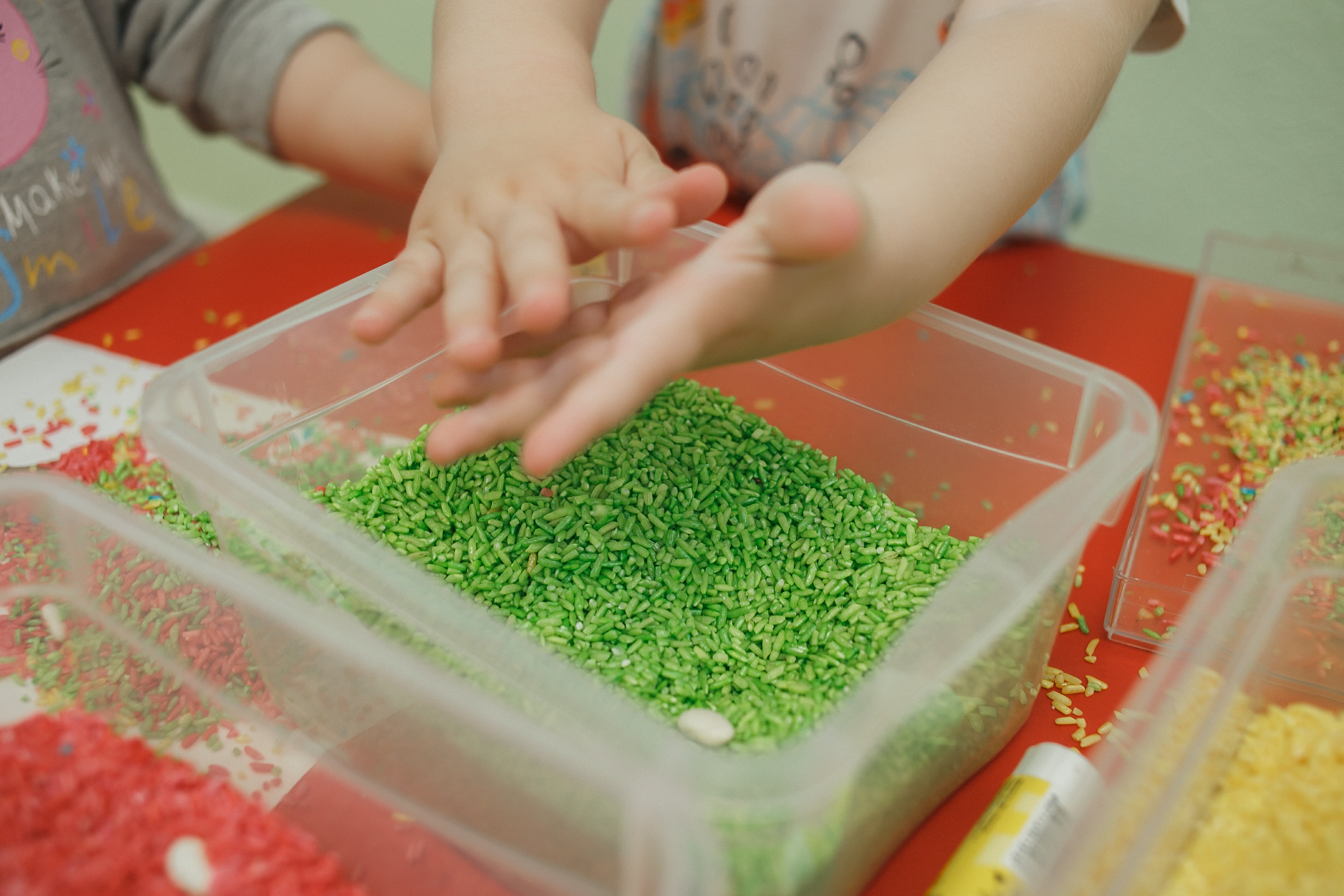 A photo of a child exploring a sensory bin